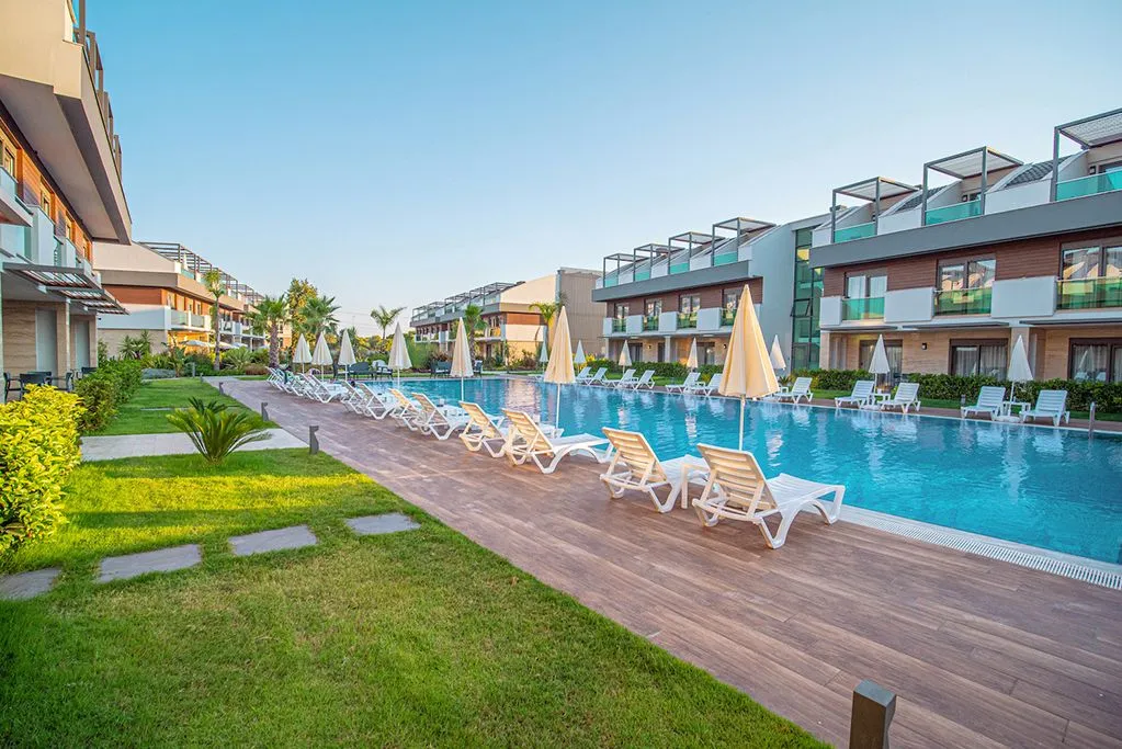 Long hotel pool with sun loungers and garden villas in Antalya
