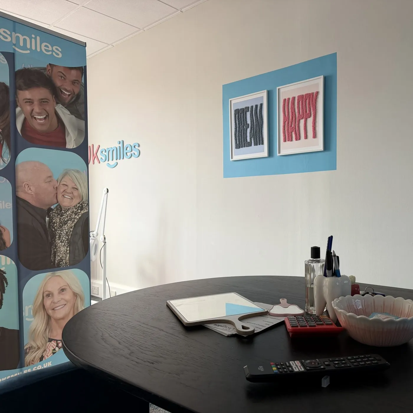 The UK Smiles consultation room in Leeds, with the table, a hand mirror, the shade guide and Dream and Happy prints on the wall