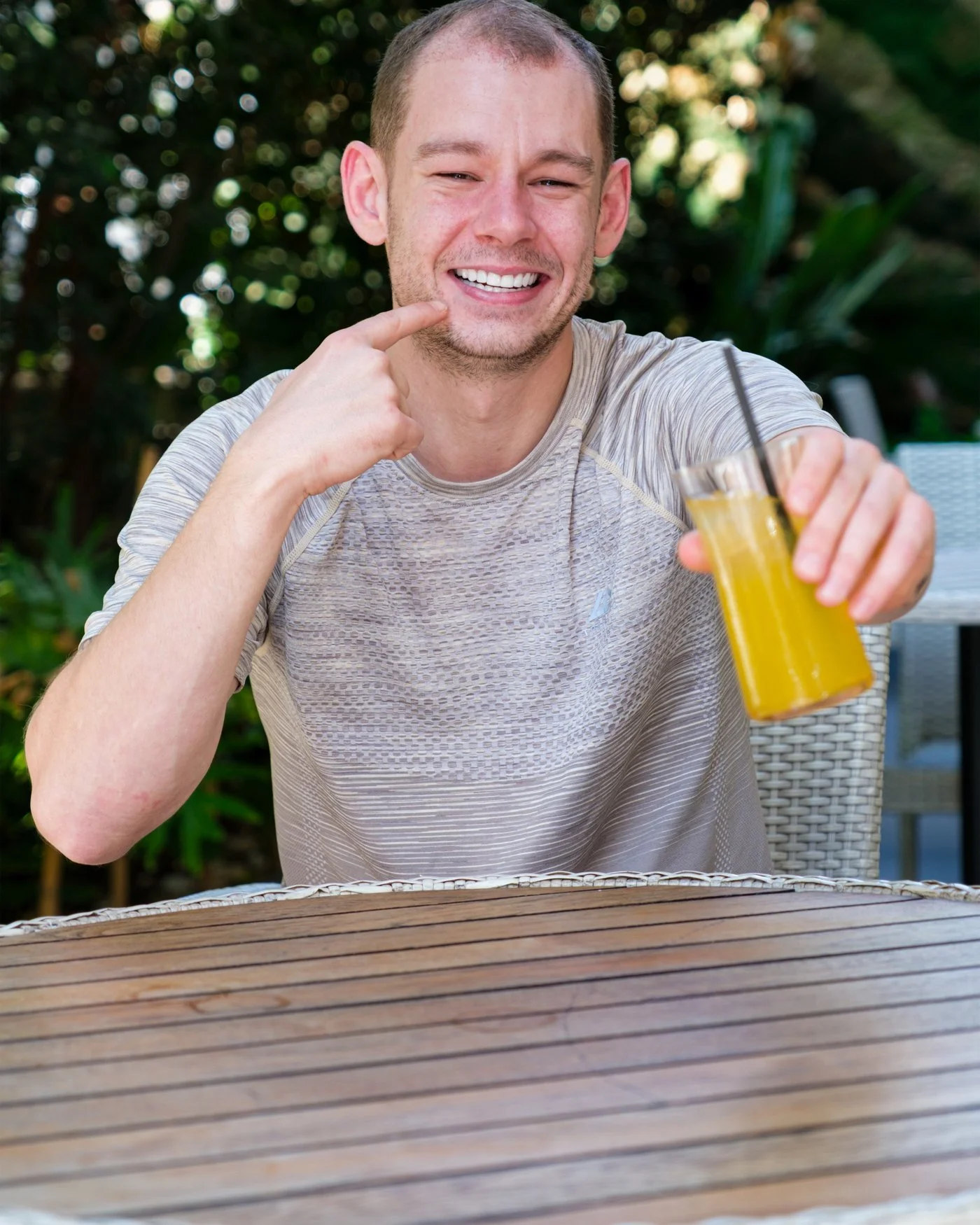 A UK Smiles patient smiling with a drink in a hotel garden in Antalya