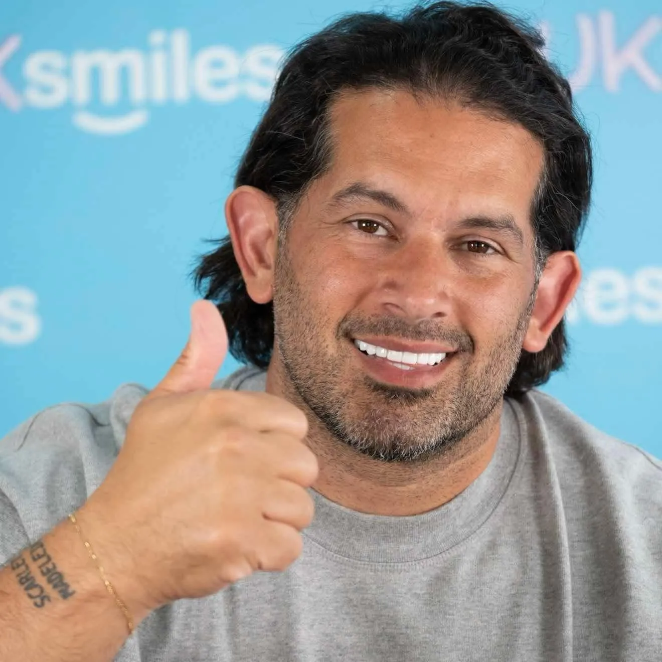 Man in a grey T-shirt giving a thumbs up with his new smile