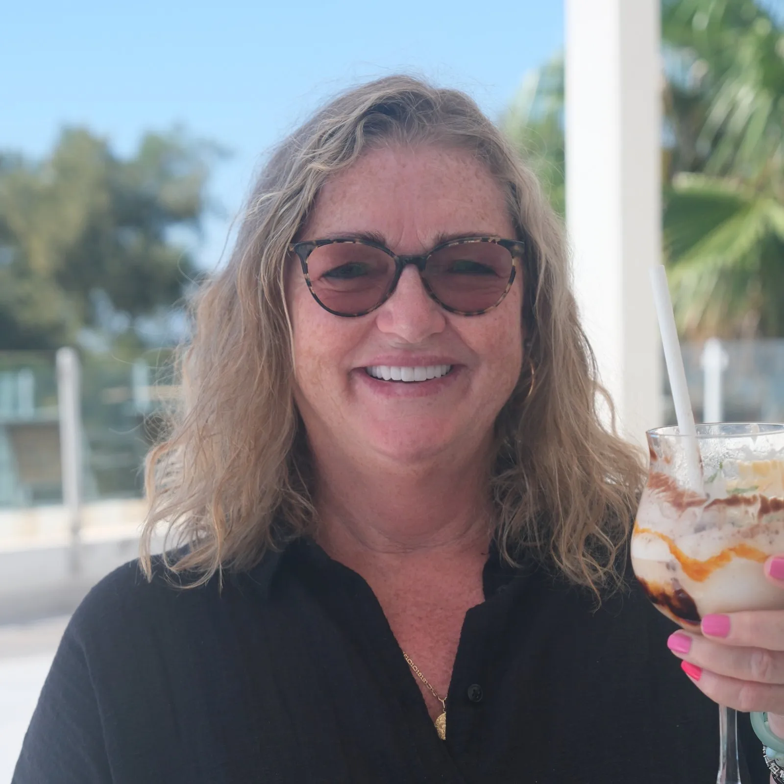 A UK Smiles patient smiling with a drink on a sunny hotel terrace in Lara