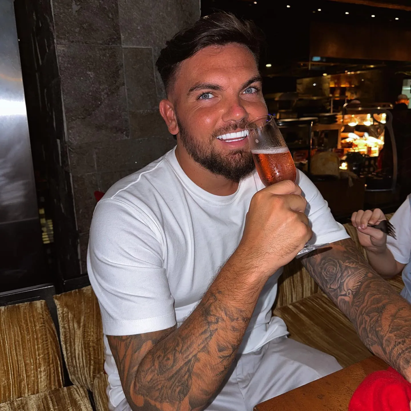 Sam Gowland smiling at a restaurant, his veneers visible