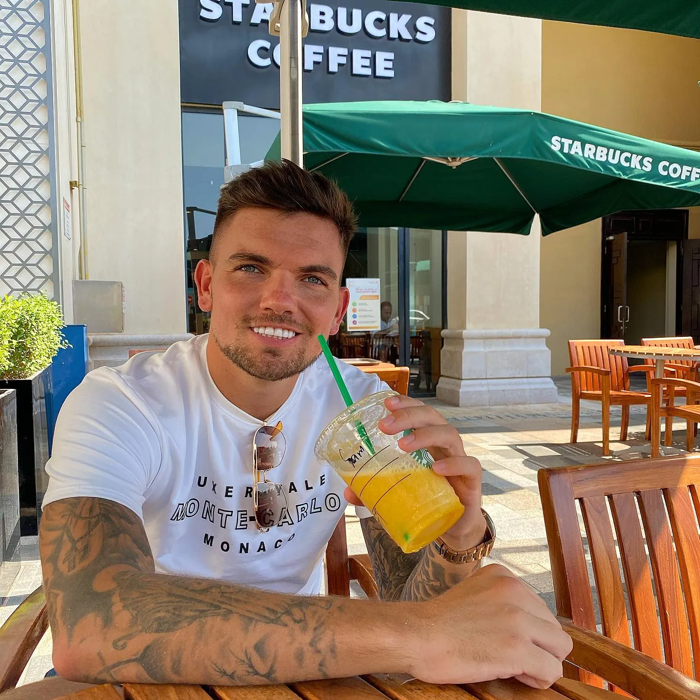 Sam Gowland smiling outdoors with a drink, showing his white smile