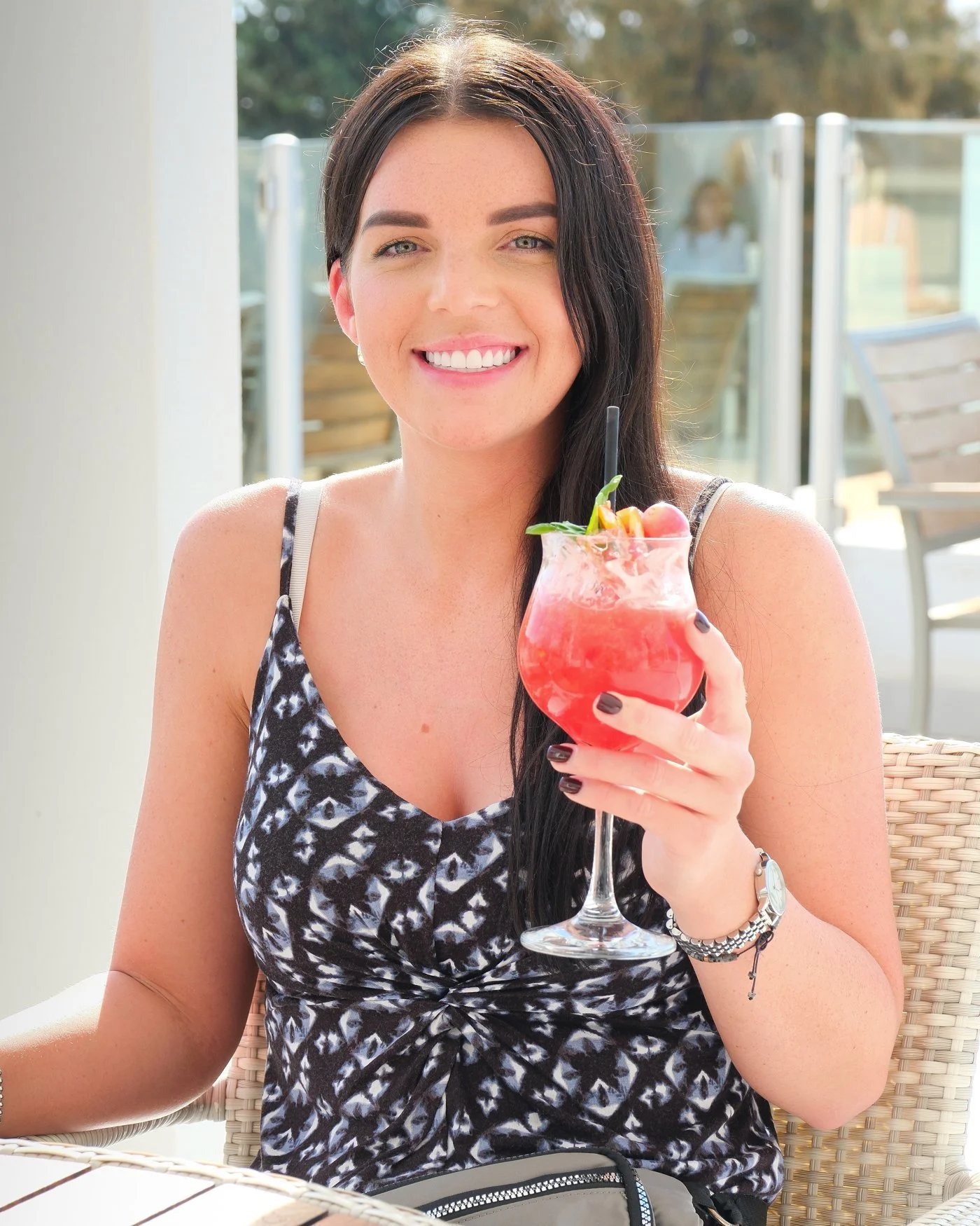A smiling UK Smiles patient with a cocktail on a hotel terrace in Antalya after her treatment