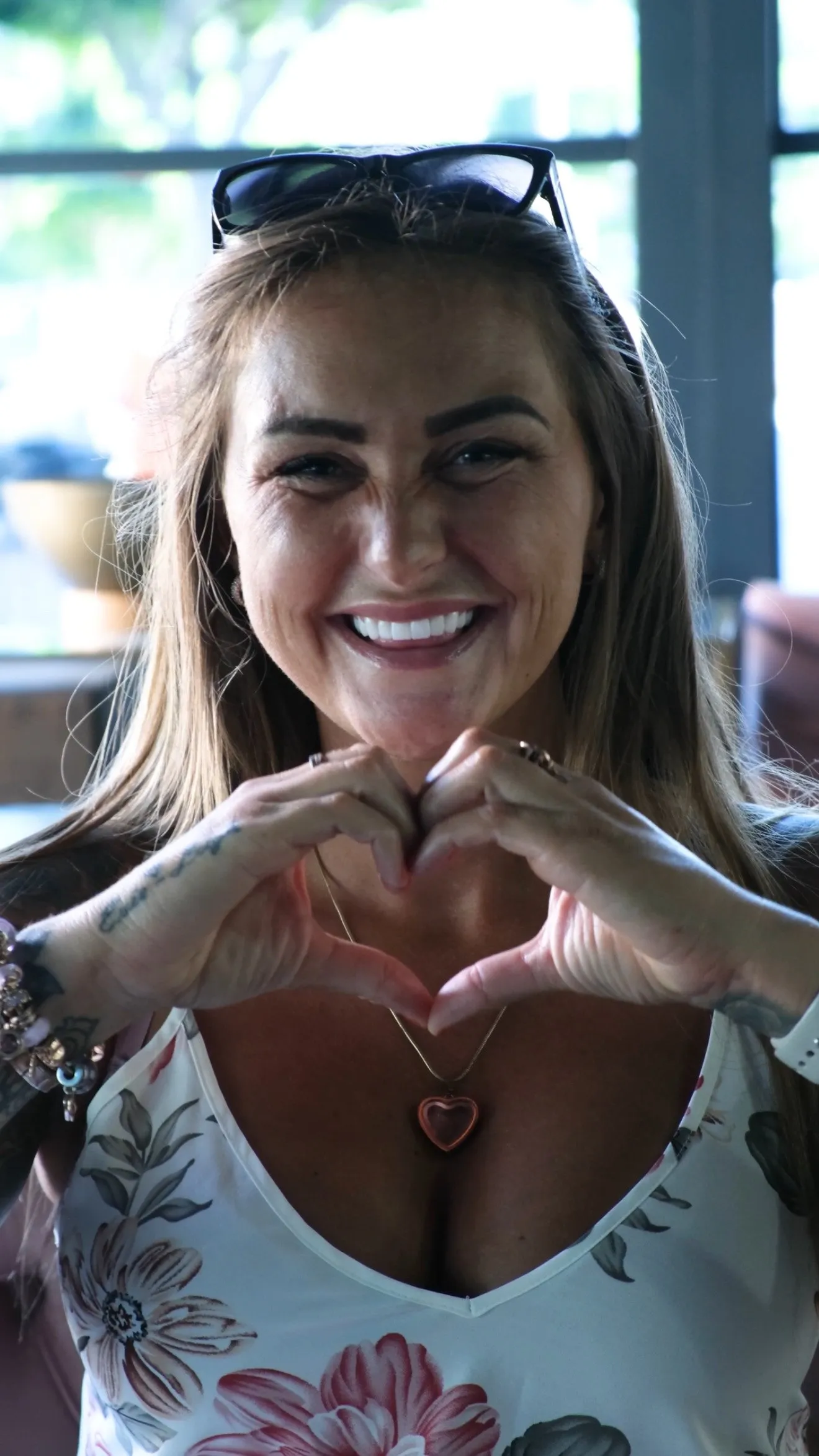 Happy UK Smiles patient making a heart with her hands and smiling with her new teeth