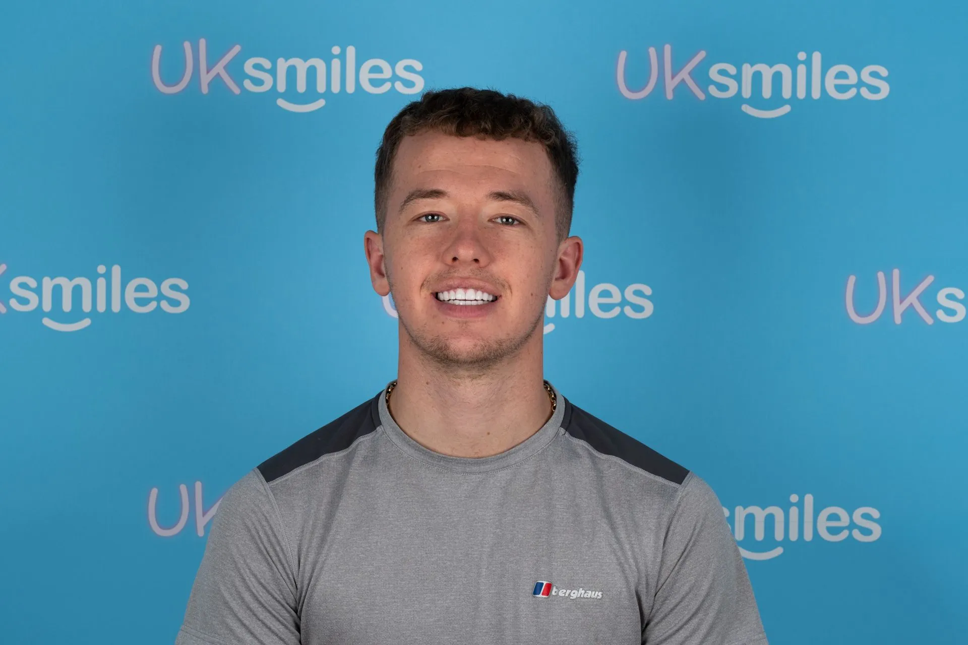Young man smiling in front of the UK Smiles backdrop after his treatment